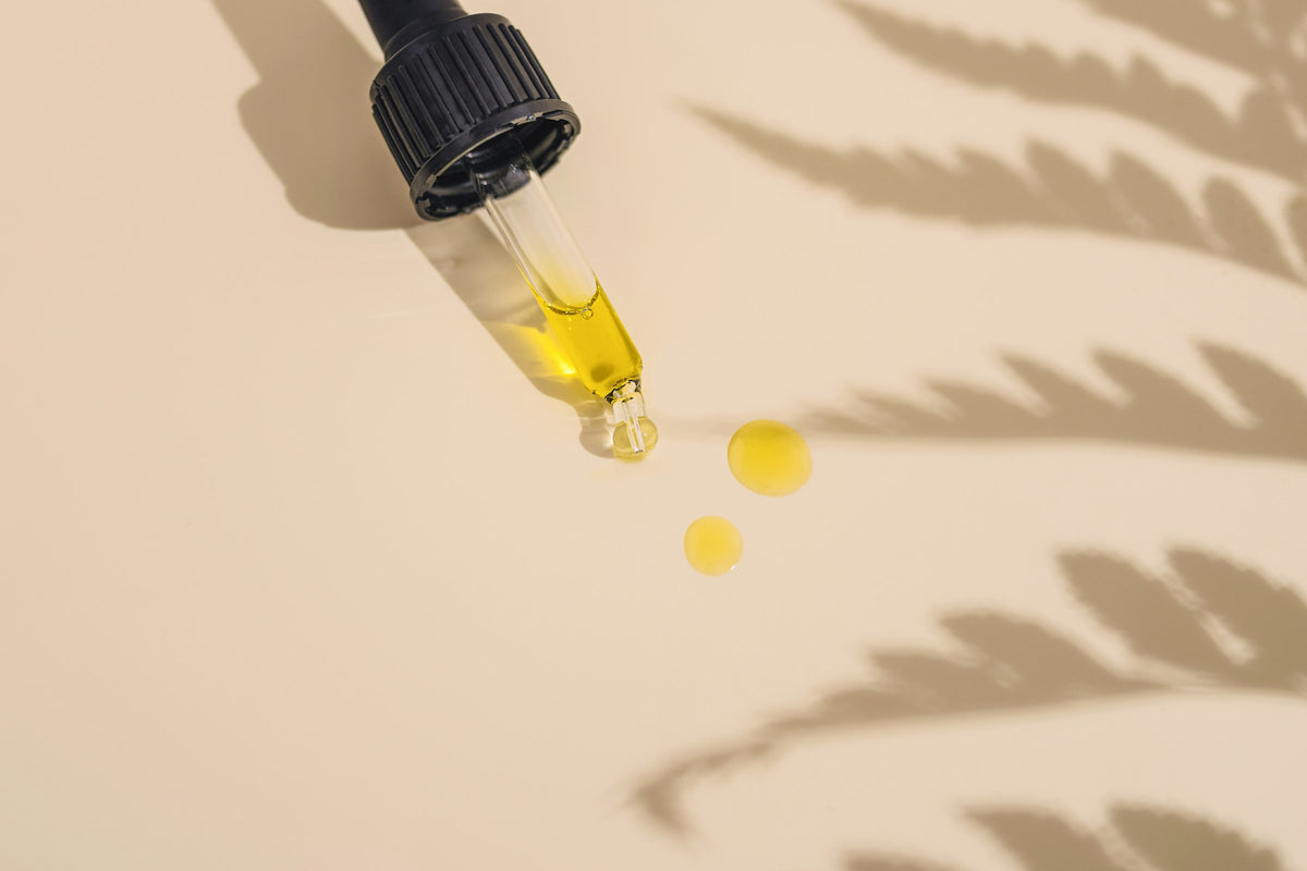 A dropper bottle of golden oil on a table